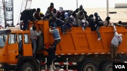 Pekerja migran asal Afrika berupaya naik ke truk setibanya di pelabuhan Misrata dalam operasi evakuasi yang diorganisir IOM.