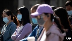 Orang-orang yang memakai masker di tengah kekhawatiran virus corona, di sebuah jalan di Beijing pada 13 Mei 2020. (Foto: AFP/Noel Celis)