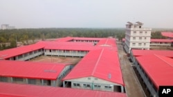 In this Dec. 19, 2019 photo, a man walks past buildings on Bhasan Char, or floating island, in the Bay of Bengal, Bangladesh.