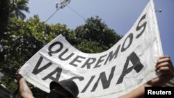 A man holds a banner reading "We want vaccine" during a protest against new measures implemented to curb the spread of the coronavirus disease in Rio de Janeiro, Brazil, March 26, 2021.