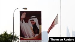 A Bahraini flag flies at half-mast as vehicle drives past a banner depicting Bahrain's veteran prime minister Sheikh Khalifa bin Salman Al Khalifa who has died, Nov. 11, 2020.