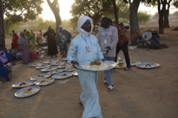 Plates of food are brought to Cameroonian refugees who are gathering in N'djamena, Chad, Dec. 10, 2021.