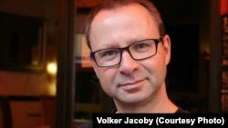 Voker Jakobi (Volker Jacoby) Yevropada Xavfsizlik va Hamkorlik Tashkiloti, shuningdek, BMTda ishlagan. Bugungi kunda Vashingtondan turib tahlilchilik qiladi.