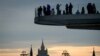 FILE - People enjoy the view from a pedestrian bridge in the Zaryadye Park, with the Kremlin's towers and the Russian Foreign Ministry headquarters seen in the background, in Moscow on March 13, 2018.