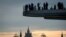 FILE - People enjoy the view from a pedestrian bridge in the Zaryadye Park, with the Kremlin's towers and the Russian Foreign Ministry headquarters seen in the background, in Moscow on March 13, 2018.