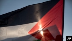 FILE - An Israeli Arab bedouin waves a Palestinian flag during a rally marking the 40th anniversary of Land Day and against a plan to uproot the village of Umm Al-Hiran, in Umm Al-Hiran, Israel, March 30, 2016.