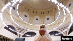 Seorang pria Saudi mengenakan masker wajah sedang menunaikan salat subuh di dalam Masjid Al-Rajhi setelah pengumuman pelonggaran locdown di tengah wabah virus corona (Covid-19) di Riyadh, Arab Saudi, 31 Mei 2020. (Foto: Reuters)