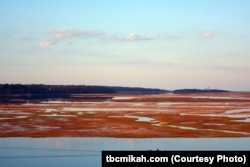 Boatmen glide past a vibrant marsh on a bay near Salt Pond Visitor Center at the Cape Cod National Seashore in Massachusetts.