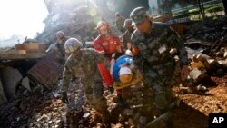 In a disaster drill, soldiers from Chinese PLA Southern Theater Command Army and the U.S. Army Pacific carry an injured man from a mock earthquake-collapsed building as they conducting a joint rescue operation in the U.S.-China Disaster Management Exchange drill at a training base in Kunming, China, Nov. 18, 2016.