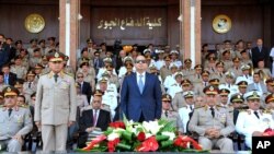 FILE - In this July 22, 2015, photo provided by the office of the Egyptian Presidency, Egyptian President Abdel-Fattah el-Sissi, (C), and Defense Minister Sedqi Sobh, (L), stand at attention at the Air Defense Academy in Alexandria, Egypt. Maj-Gen. Mohammed Ali el-Sheikh, an Egyptian army general who retired about 18 months ago, has been named the country’s supply minister.
