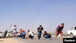 Protesters hide during an attack on a Libyan militia, the Libya Shield brigade, headquarters in Benghazi, June 8, 2013. 