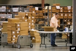 An employees at the Palm Beach County Supervisor of Elections office feed ballots through a machine as he count votes during a recount, Nov. 14, 2018, in West Palm Beach, Florida.