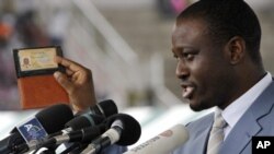 Prime Minister of Ivory Coast Guillaume Soro displays his identity card as he speaks during a rally at a stadium in Bouake on 3 Oct 2010