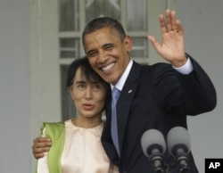 US President Barack Obama (R) waves as he embraces Burmese democracy activist Aung San Suu Kyi after addressing members of the media at Suu Kyi's residence in Rangoon, Burma, November 19, 2012.