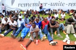 People follow the proceedings of the 20th anniversary commemoration of the Rwandan genocide, in Kigali April 7, 2014.