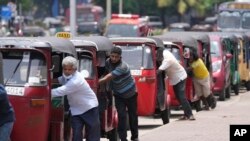 Sri Lankan auto rickshaw drivers queue up to buy petrol near a fuel station in Colombo, Sri Lanka, April 13, 2022. Sri Lankans are facing a severe economic crisis that has ravaged household budgets amid high inflation. Staple foods are in short supply, along with medicines.
