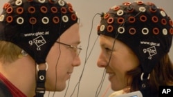 In this file photo, models use a brain computer interface to talk to each other by a laptop computer at the Medica 2006 fair in Duesseldorf, western Germany, Tuesday, Nov.14, 2006. (AP Photo/Frank Augstein)