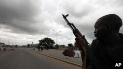 A pro-Ouattara fighter from a group which calls itself the "invisible commandos" patrols a street in northern Abidjan's Abobo district (Mar 26 2011