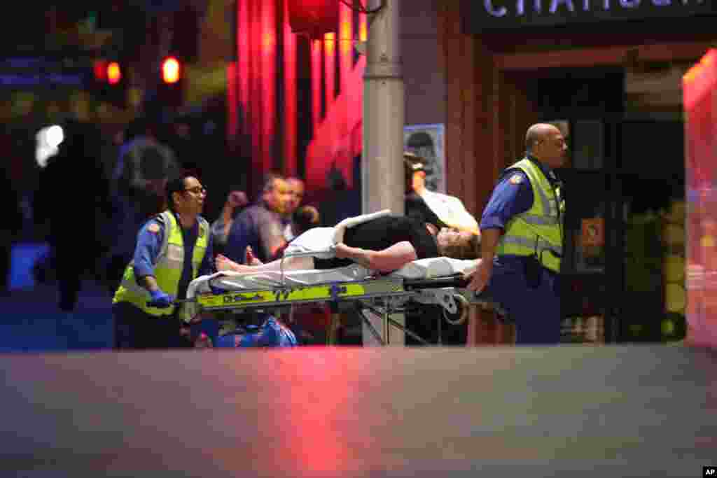 A injured hostage is wheeled to an ambulance after shots were fired during a cafe siege at Martin Place in the central business district of Sydney, Dec. 16, 2014.