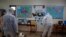 Workers wearing protective suits spray disinfectant inside a classroom at a primary school in Athens, March 9, 2020. 
