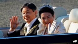 Kaisar Naruhito dan Ratu Masako melambai kepada warga yang menunggunya di sepanjang jalan di Tokyo hari Minggu (10/11). 
