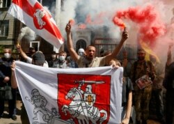 People light flares and wave Belarusian flags to support Belarusian opposition in front of Belarusian Embassy in Kyiv, Ukraine, Aug. 14, 2020.