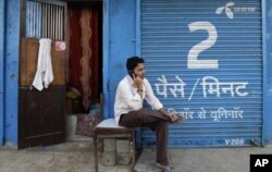 បុរស​ម្នាក់​សន្ទនា​តាម​ទូរស័ព្ទដៃនៅ​មុខហាង​ទំនិញ​បិទទ្វារ។