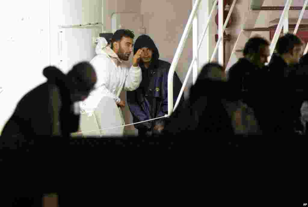 Mohammed Ali Malek (left) and Mahmud Bikhit (right), two of the survivors of the boat that overturned off the coast of Libya over the weekend, wait to disembark from Italian Coast Guard ship Bruno Gregoretti, at the port of Catania, Italy, April 20, 2015. The two were later identified as captain and crew member of the sunken vessel.
