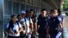 FILE - U.S. Customs and Border Patrol officials wait to hand asylum seekers over to Mexican officials as they are returned under the so-called Remain in Mexico program, on the international bridge between Laredo, Texas, and Nuevo Laredo, Mexico, July 10, 