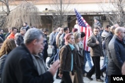 A man carries an American flag during an anti-government protest in Pristina, Kosovo. Many Kosovars see America as an “ideal model” of democracy, Jan. 9, 2016. (P.W. Wellman/VOA)