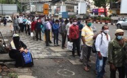 People wearing face masks as a precaution against the coronavirus wait at a bus stop in Mumbai, India, June 7, 2021.