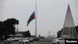 An Azeri state flag flies at half-mast as the country observes the day of national mourning for the victims of an Azerbaijan Airlines' Embraer passenger plane crash near the Kazakh city of Aktau, in a square in Baku, Dec. 26, 2024. 