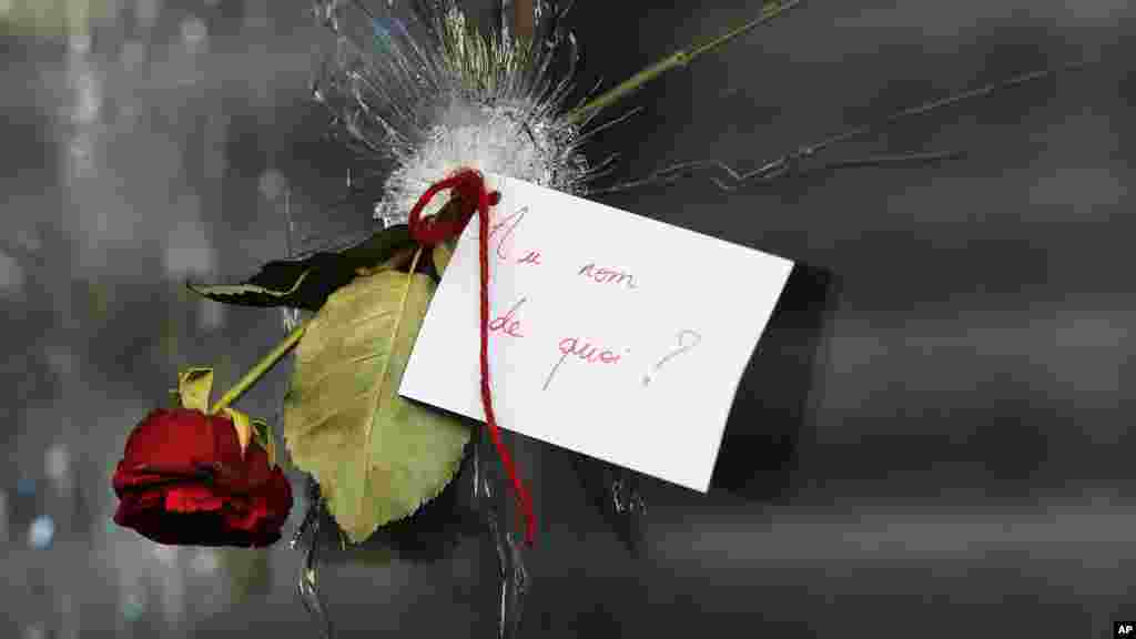 ጥይት በበሳው መስታወት ሰዎች ሃዘናቸውን ሲገልጹ &quot;በምን ስም?&quot; ወይም በእንግሊዝኛ &quot;In the name of what?&quot; የሚል በፈረንሳይኛ የተፃፈ ጥያቄ አቅርበዋል። ይህ በፓሪስ የሽብር ጥቃት ከደረሰባቸው ቦታዎች አንዱ ሩ ደ ሻሮን &nbsp;(Rue de Charonne) የሚባል ምግብ ቤት ነው። [አሶሽየትድ ፕረስ ፎቶ/AP Photo/ፍራንክ አጎስቲን/Frank Augstein]