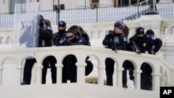 پلیس کنگره تظاهرکنندگان را که تلاش می کردند موانع پلیس را پشت سر بگذراند زیر نظر دارند. واشنگتن، ۶ ژانویه ۲۰۲۱