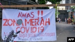 Anak-anak bermain di luar kawasan pemukimannya di Jakarta, yang diisolasi setelah sebagian warganya terpapar virus corona COVID-19, 22 Juni 2021. (Foto: BAY ISMOYO/AFP)