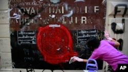 An anti-government protester volunteers to clean graffiti debris from the main gate of the Royal Thai Police Headquarters in Bangkok, Thailand, March 1, 2014. 