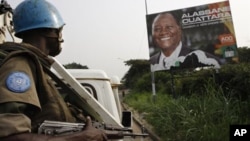 United Nations troops from Niger drive past a billboard of Ivory Coast's internationally recognized elected leader Alassane Ouattara during a patrol in Abidjan, Ivory Coast, 4 Jan 2011