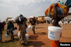 FILE - People displaced by the recent unrest, collect food distributed by aid agencies at an IDP camp at the Mpoko international airport of Bangui, Feb. 12, 2014.