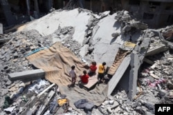 Watoto wa Kipalestina wakicheza katika uwanja wa jengo lililobomolewa na mashambulizi yaliyofanywa na jeshi la Israeli na kuwaokoa mateka wanaodaiwa walikuwa wanashikiliwa humo, katikati ya Ukanda wa Gaza Juni 15, 2024.