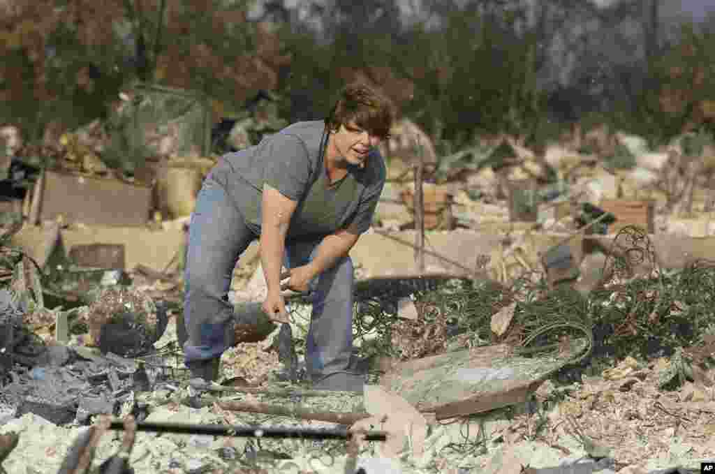 Tammy Christiansen searches the remains of her Coffey Park neighborhood home, Oct. 11, 2017, in Santa Rosa, California. During her search she found her wedding ring and her son's wrestling trophy. 
