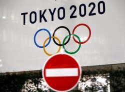 FILE - A banner for the Tokyo 2020 Olympics is seen behind a traffic sign, following an outbreak of the coronavirus disease (COVID-19), in Tokyo, Japan, March 23, 2020.