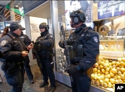 Counterterrorism officers stand in front of a watch store in Times Square, Dec. 29, 2016, in New York, as they take shelter from the rain.