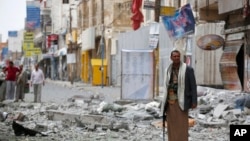 A Shiite fighter known as a Houthi stands guard in front of buildings destroyed by a Saudi-led airstrike in Sana'a, Sept. 5, 2015. 