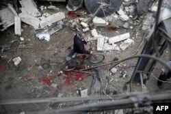 A Syrian man walks with a bicycle amid the rubble of destroyed buildings following a reported air strike by Syrian government forces in the rebel-held area of Douma, east of the capital Damascus, on Oct. 29, 2015.