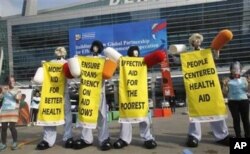 In Busan, members from Save The Children and World Vision stage a demonstration urging donor countries to fulfill their aid commitments.