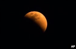 The moon turns a reddish hue as it passes through the earth's shadow during a lunar eclipse as seen in Gauhati, India, Jan. 31, 2018.