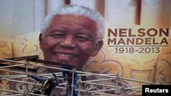 An image of Nelson Mandela is displayed on a digital screen as workers on scaffolding construct a stage ahead of Mandela's national memorial service at First National Bank (FNB) Stadium, also known as Soccer City, in Johannesburg, Dec. 9, 2013.