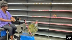 A shopper passes by empty shelves in the bread section of a Walmart, Sept. 25, 2024 in Tallahassee, Fla.