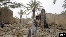Seorang korban yang selamat dari gempa, menggendong seekor kambing yang ditemukannya diantara reruntuhan rumah di wilayah Mashkail, propinsi Baluchistan (17/4).