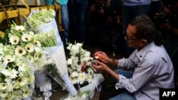 A Bangladeshi social activist lights a candle on floral arrangement that he placed on a road block leading to the Holey Artisan Bakery, the scene of a fatal attack and siege, in Dhaka on July 3, 2016.